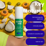 A bottle of Olivia + Eve Advanced Antioxidant Cream stands on a person's stomach against a bright yellow background with coconut halves, apricots, and olives scattered around. White text on the right reads 'Key features' with four dark blue callouts: dermatologically approved, clinically tested, suitable for sensitive skin, and safe for skin.