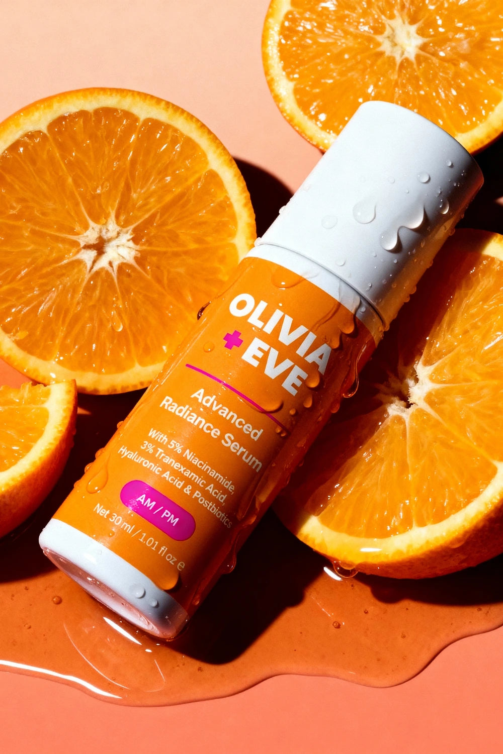 Olivia + Eve Advanced Radiance Serum bottle surrounded by sliced oranges on a peach background
