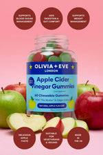 Bottle of Olivia + Eve London Apple Cider Vinegar Gummies with apples on a pink background