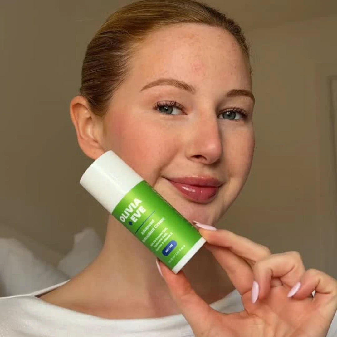 Woman holding an Olivia + Eve Advanced Antioxidant Cream skincare product with a neutral background