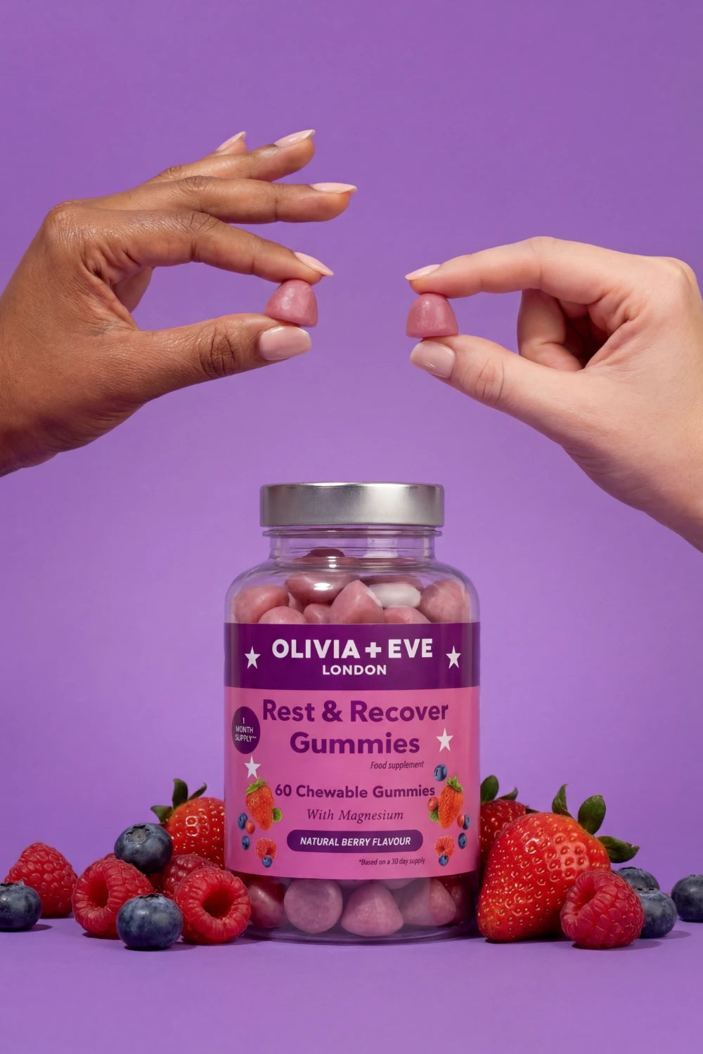 Bottle of Olivia + Eve Rest & Recover Gummies with hands reaching towards it on a purple background