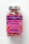 Jar of pink gummies labeled 'Olivia + Eve London Rest & Recover Gummies' on a white background
