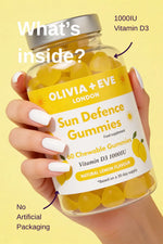 Hand holding a bottle of Olivia + Eve Sun Defence Gummies with lemon flavor on a yellow background.